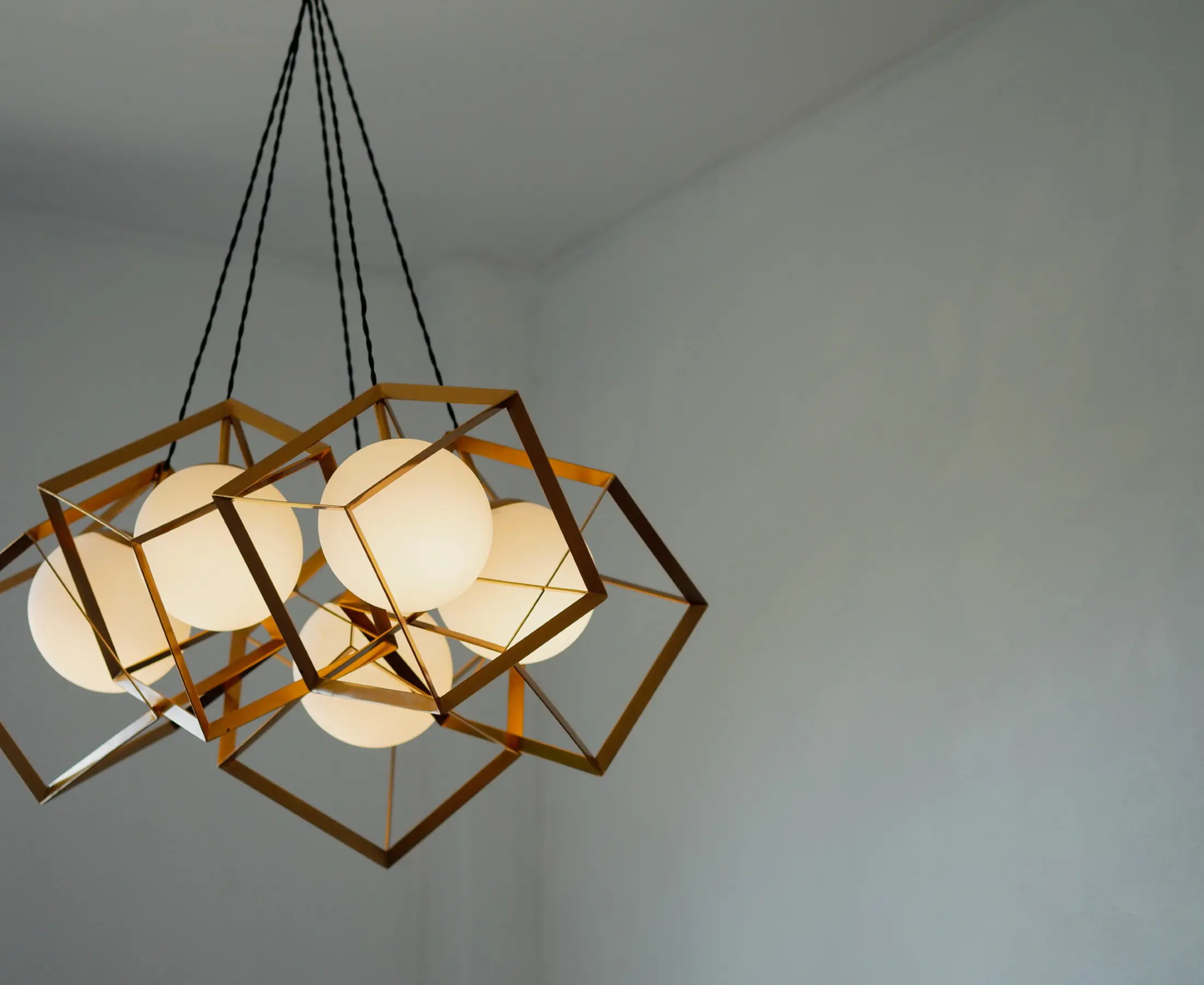 Modern geometric chandelier with glowing bulbs.